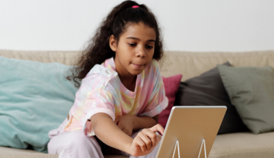 A child reaching towards a tablet on a stand