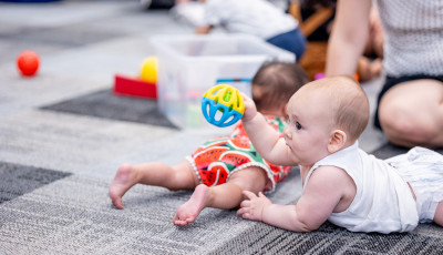 baby plays with a toy at the library
