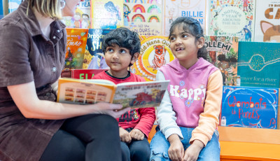 two children looking at a book with an adult