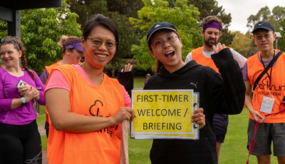 two people holding a sign saying First-time welcome/ briefing