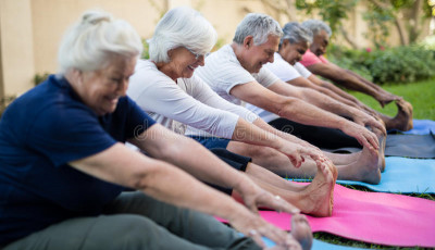 a line of people are sitting with their legs stretched out reaching for their toes