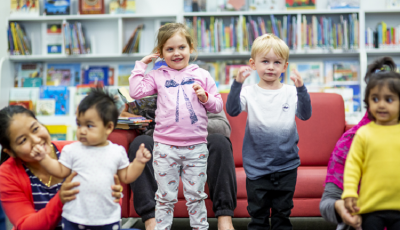 Children standing in the library, smiling and singing.