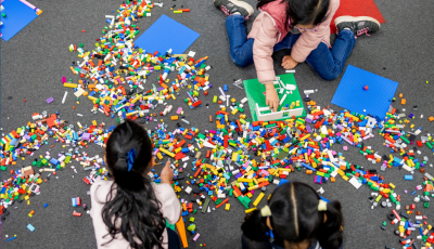 Three girls sitting on the floor playing with Lego.