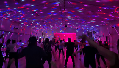 Lots of people dancing in the dark with coloured disco lights on the ceiling