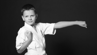 a boy in a karate outfit is standing with one hand straight to look like a punch