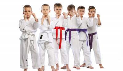 a group of boys and girls stand wearing a karate outfit