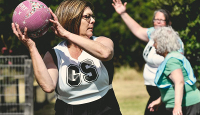 a woman wearing glasses holds a ball up ready to throw