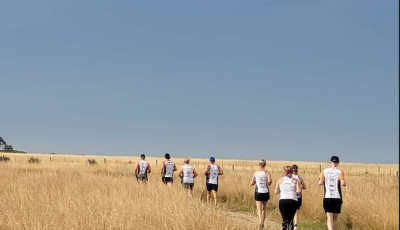 a group of people are running away from the camera through a field