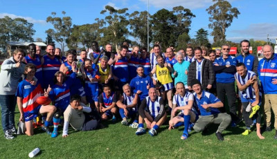 a group of adult males wearing blue red and white sports kits smile at the camera