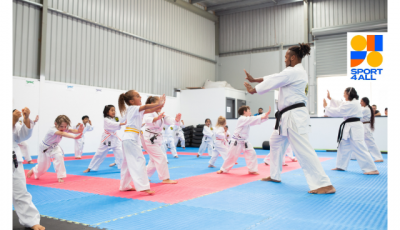 a group of children in martial arts uniform face three instructors