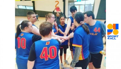 7 children wearing blue tops are standing in a circle with their hands in the middle