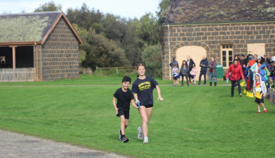 two children are running together, they are both holding a guiding strap