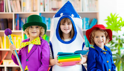 3 children wearing costumes, a magician, a rocket ship holding books, and paddington bear