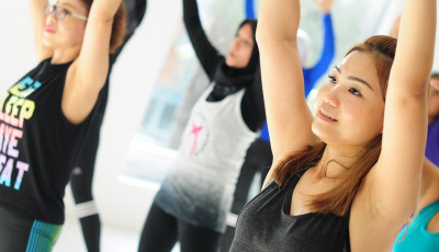 a group of women in an exercise class are reaching up