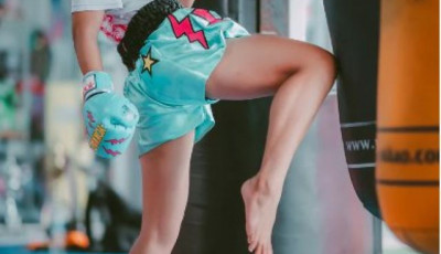 a girl is lifting her knee up to hit a punch bag