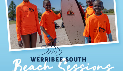 a group of children wearing orange tops are holding up a surf board on the beach