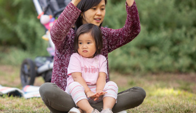 Mother and toddler performing hand actions in outdoor setting