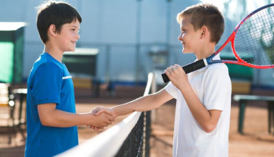 two boys are shaking hands over a tennis net