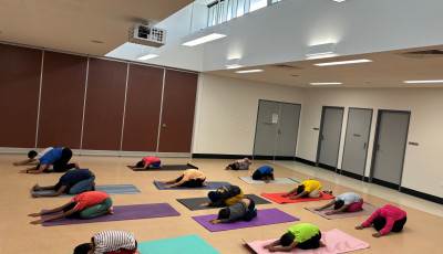 a group of children on yoga mats are kneeling back with their hands stretched out infront on the floor in a Yoga pose
