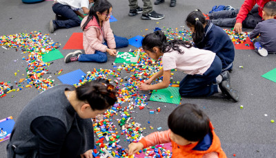 Children and parents building with Lego on the floor.