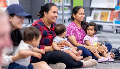 Mothers and children sitting on the floor in the library.