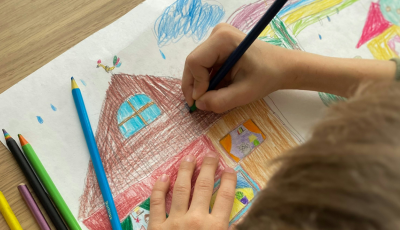 Child drawing a house with pencils 