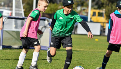two children are running towards a football