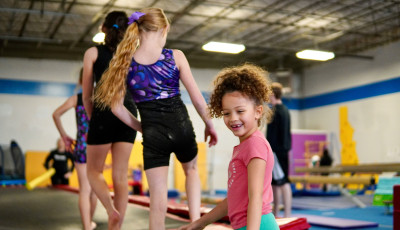 kids are climbing onto gym equipment in a queue and smiling
