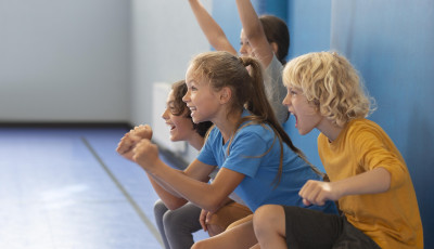 children are doing squats leaning against a wall and cheering