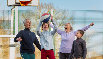 two young kids and two grandparents are cheering and holding a basketball