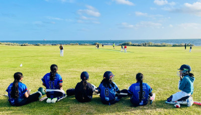 a group of kids are sitting waiting to play cricket
