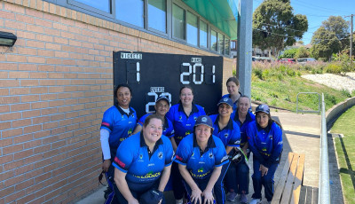 a group of women in blue team cricket uniforms are gathered infront of a scoreboard