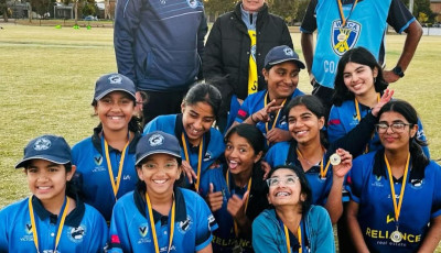 a group of girls in cricket kit are smiling at the camera