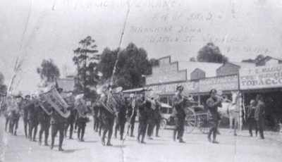 A black and white photo of the RAAf band marching down Watton Street in 1923, with shop front visible n the background and some faint writing on the top of the image.  