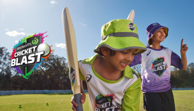 a kids is preparing to hit a ball while another kids cheers in the background