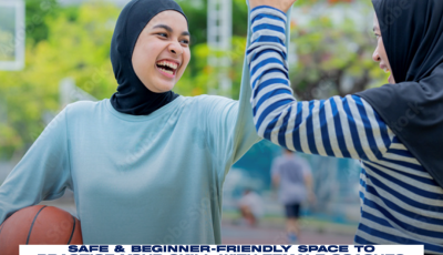 two women wearing hijab are high fiving, one is holding a basketball