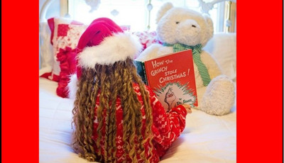 Child reading Christmas book to teddy bear