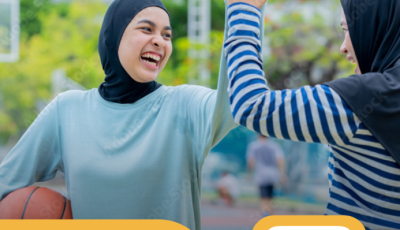 two women wearing hijabs are high fiving each other and holding a basketball