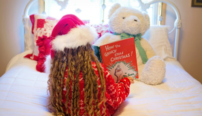 Child reading Christmas book to teddy bear