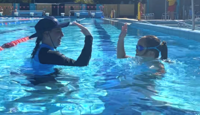 a swimming teacher gives a girl a high 5 in the pool