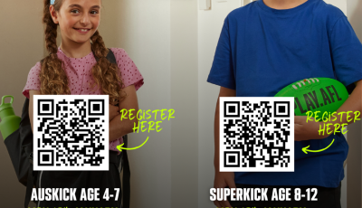 two kids holding green AFL balls are smiling at the camera