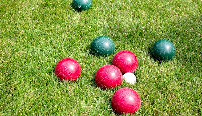 red and green lawn bowls are clustered around a white jack ball