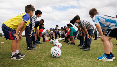 two children in lines facing each other are watching a white football