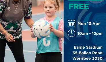 a girl holds a netball whilst a coach is talking to her