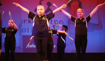 a group of girls dressed in black are standing on a stage with their arms held high